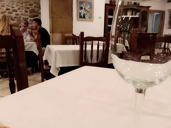 El comedor con manteles blancos y la pared de piedra al fondo.